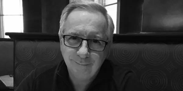 Portrait of a man with glasses in a dimly lit setting.