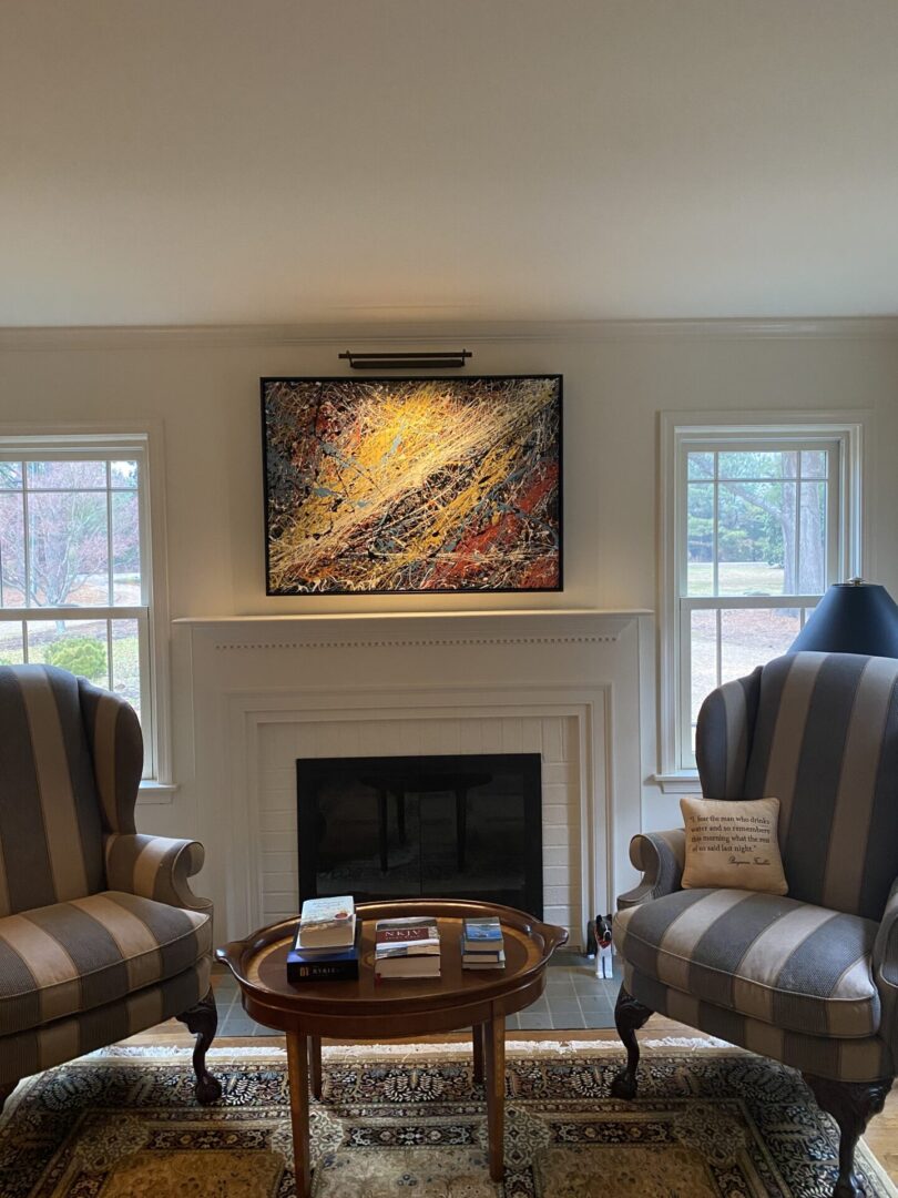 Cozy living room with striped armchairs, a fireplace, and abstract art above it.